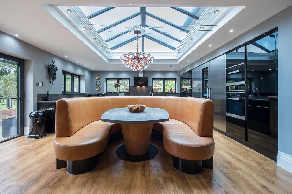 Cette image montre une salle à manger ouverte sur le salon design de taille moyenne avec un mur gris, un sol en bois brun et un sol marron.