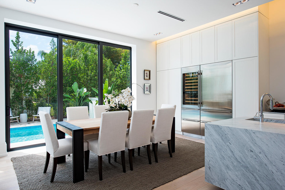 Aménagement d'une salle à manger ouverte sur la cuisine contemporaine avec un mur blanc et parquet clair.