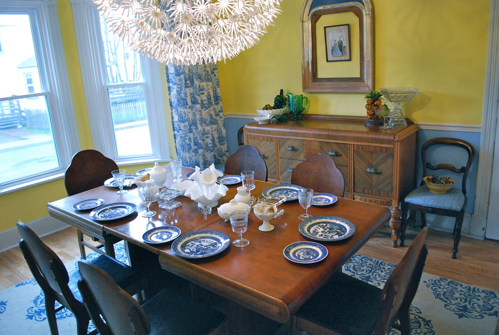 Foto de comedor clásico con paredes amarillas, suelo de madera en tonos medios y cortinas