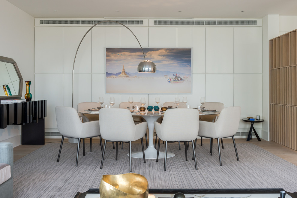 This is an example of a contemporary dining room in London with white walls, light hardwood flooring and beige floors.