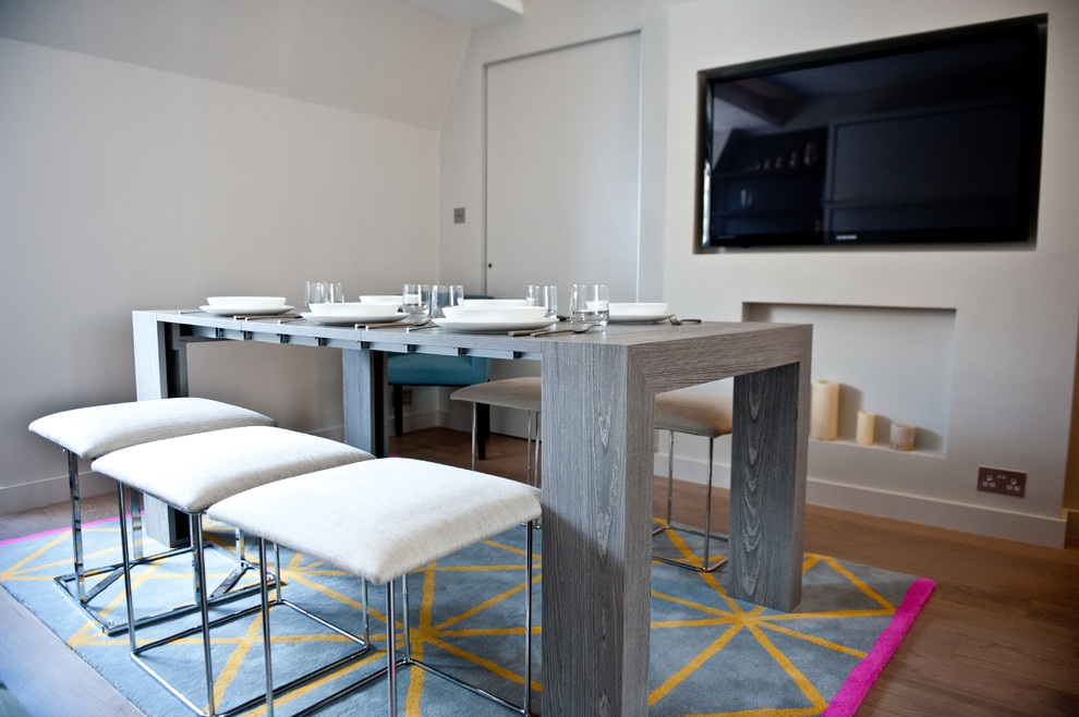 Foto di una piccola sala da pranzo minimalista chiusa con pareti bianche, parquet scuro, camino classico e cornice del camino in intonaco