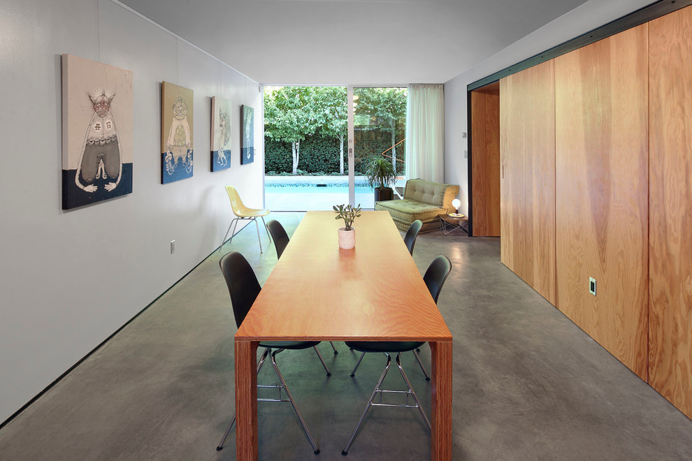 Idée de décoration pour une salle à manger design avec un mur blanc et sol en béton ciré.