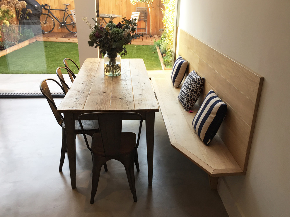 На фото: кухня-столовая среднего размера в современном стиле с белыми стенами и бетонным полом без камина