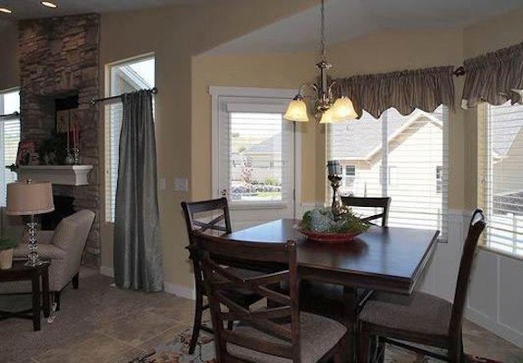На фото: кухня-столовая с желтыми стенами, полом из керамической плитки, стандартным камином и фасадом камина из камня с