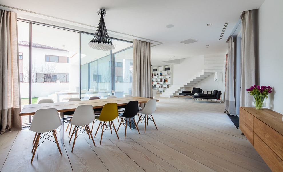 Immagine di una sala da pranzo aperta verso il soggiorno scandinava con pareti bianche, parquet chiaro e nessun camino