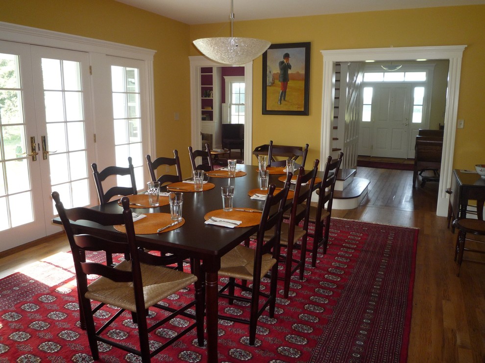 Cette image montre une salle à manger rustique fermée et de taille moyenne avec un mur jaune, un sol en bois brun, aucune cheminée et un sol marron.