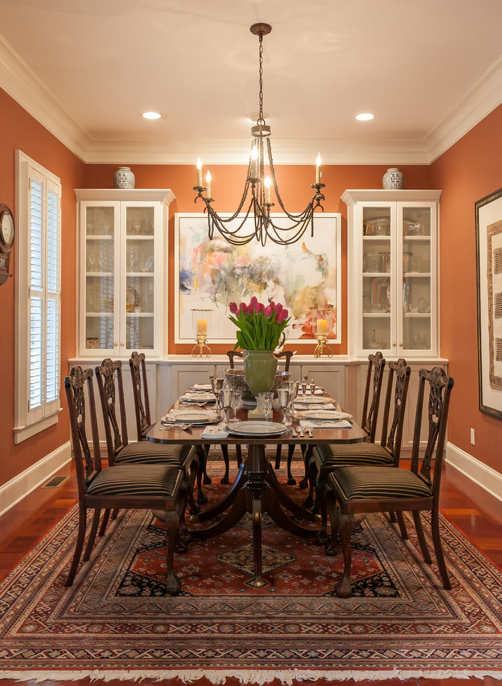 На фото: кухня-столовая среднего размера в классическом стиле с оранжевыми стенами и паркетным полом среднего тона с