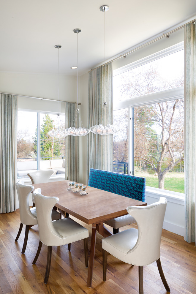 Immagine di una sala da pranzo aperta verso il soggiorno minimal di medie dimensioni con pareti bianche, pavimento in legno massello medio e nessun camino