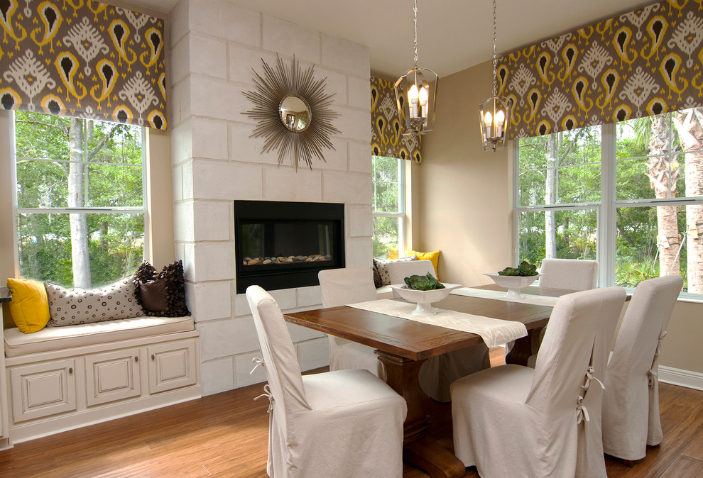 Klassisches Esszimmer mit beiger Wandfarbe, hellem Holzboden, Kamin, Kaminumrandung aus Beton und beigem Boden in Tampa