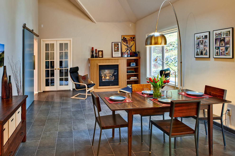 Idee per una sala da pranzo aperta verso la cucina minimalista con pareti beige, pavimento in gres porcellanato, camino classico e cornice del camino in legno