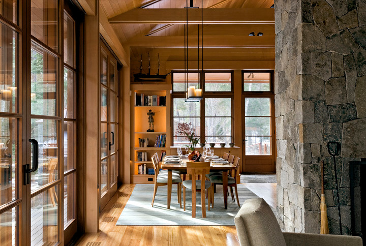 Inspiration pour une salle à manger ouverte sur le salon craftsman de taille moyenne avec un sol en bois brun, une cheminée standard et un manteau de cheminée en pierre.
