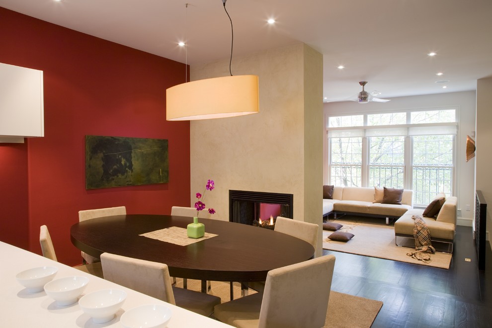 Cette photo montre une salle à manger ouverte sur le salon tendance avec un mur rouge et une cheminée double-face.