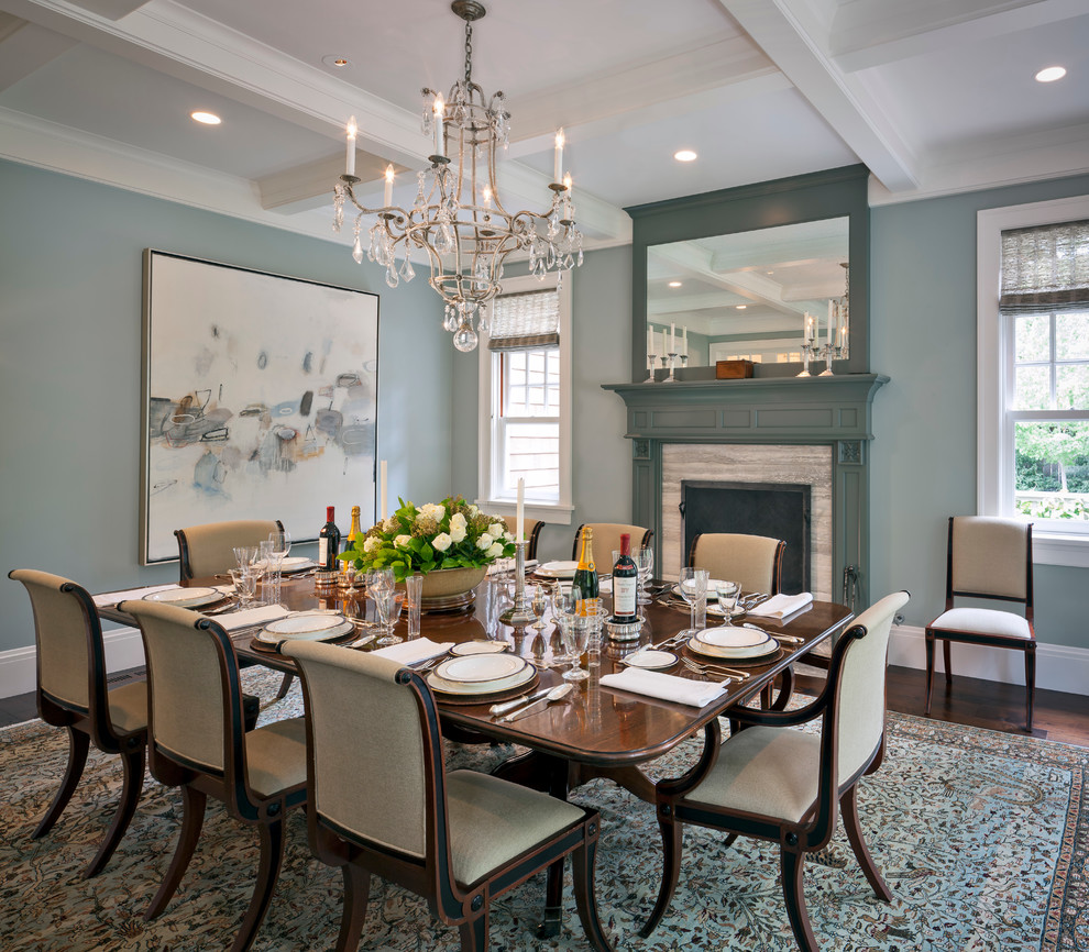 Exemple d'une grande salle à manger ouverte sur le salon chic avec un mur bleu, parquet foncé, une cheminée standard, un manteau de cheminée en pierre, un sol marron et un plafond à caissons.