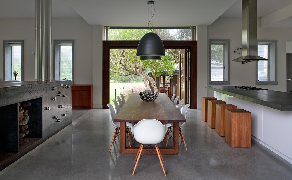 Idées déco pour une salle à manger ouverte sur la cuisine contemporaine avec un mur blanc et sol en béton ciré.