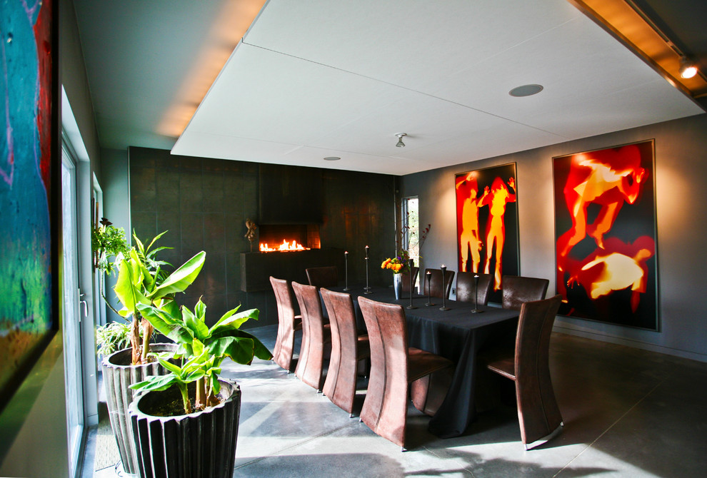 This is an example of a large contemporary dining room in Baltimore with concrete flooring, grey walls, a hanging fireplace, a metal fireplace surround and grey floors.