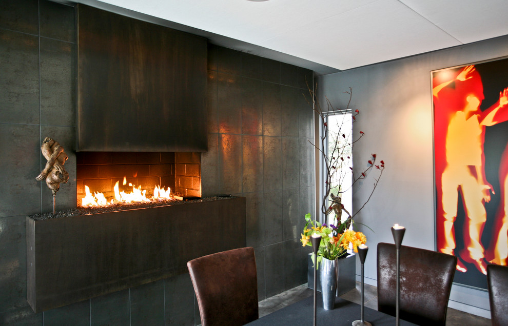 Large contemporary dining room in Baltimore with concrete flooring, grey walls, a metal fireplace surround, grey floors and a hanging fireplace.
