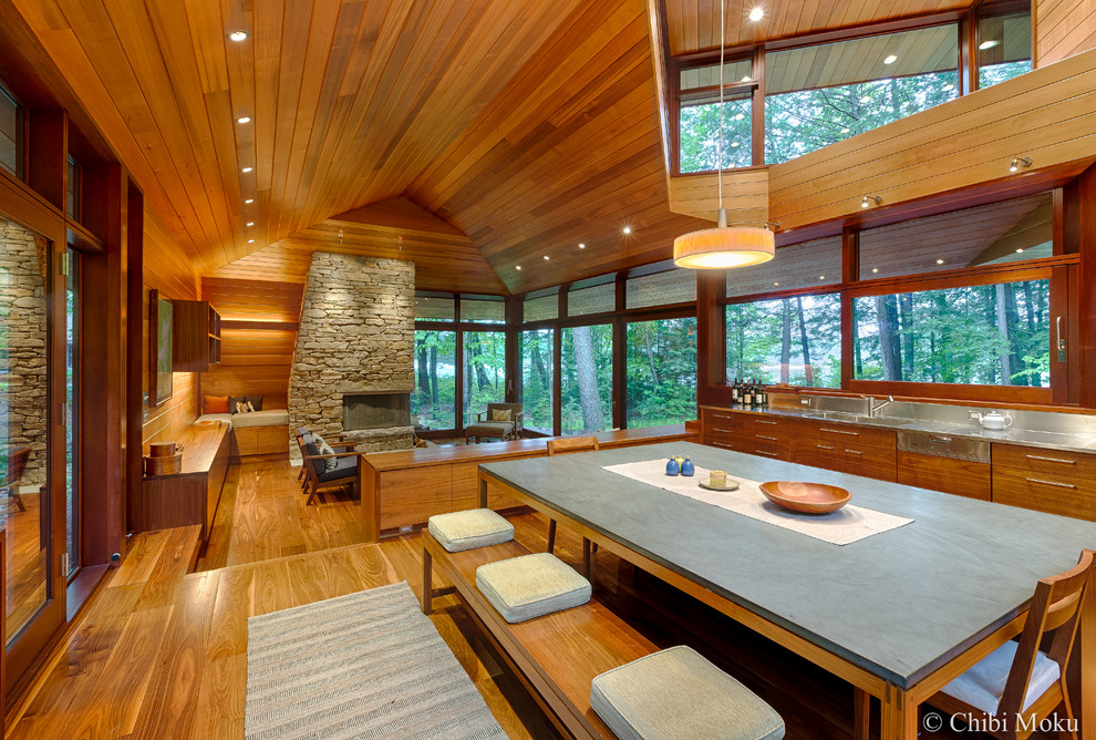 Mittelgroße Moderne Wohnküche mit braunem Holzboden, Tunnelkamin und Kaminumrandung aus Stein in Boston