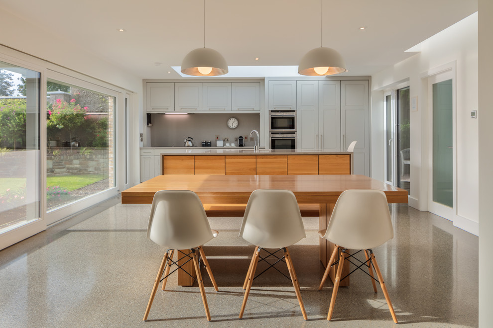 Idee per una sala da pranzo aperta verso la cucina contemporanea con pareti bianche, pavimento in cemento e pavimento grigio