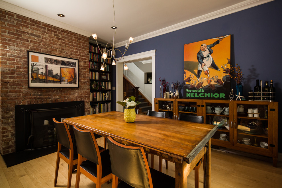 Trendy medium tone wood floor dining room photo in New York with blue walls, a standard fireplace and a brick fireplace