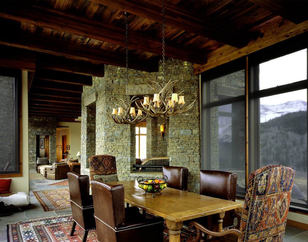 Immagine di una sala da pranzo aperta verso il soggiorno stile rurale di medie dimensioni con pavimento in ardesia, pareti beige, nessun camino e pavimento grigio