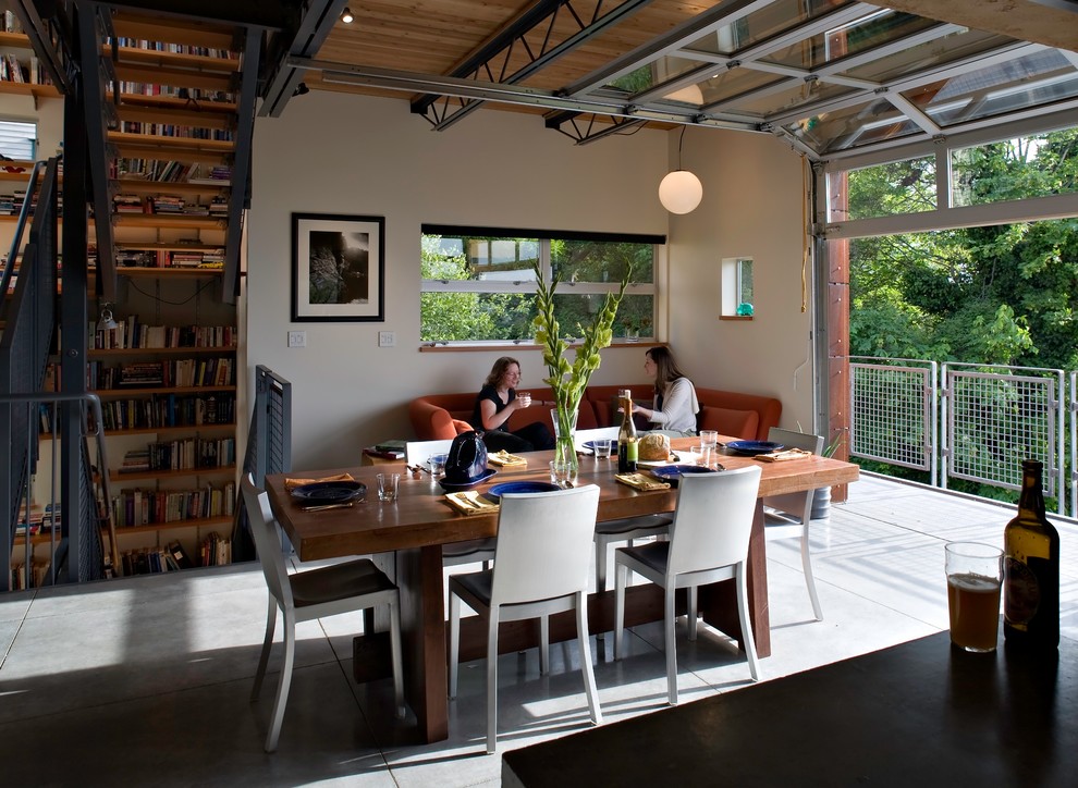 Esempio di una sala da pranzo aperta verso il soggiorno industriale di medie dimensioni con pavimento in cemento e pareti bianche