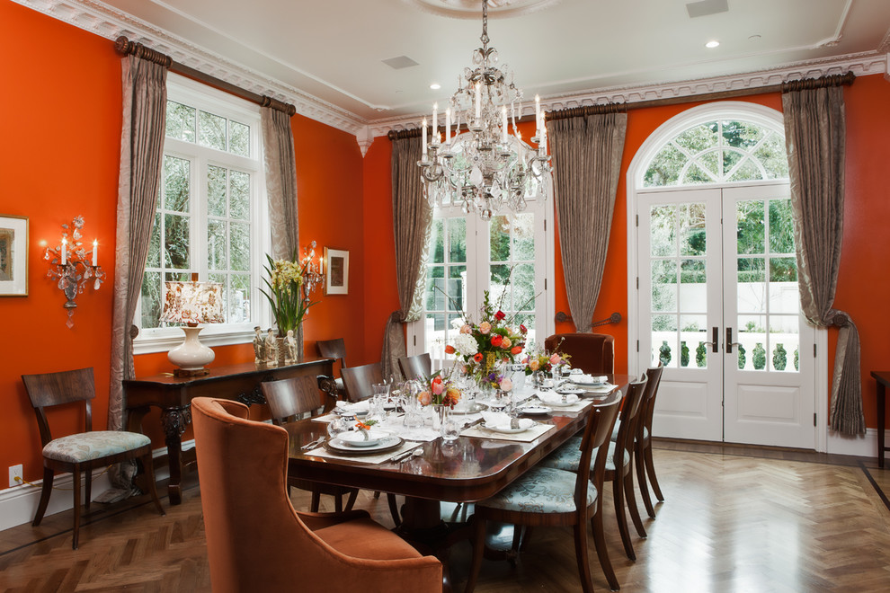 Cette image montre une rideau de salle à manger traditionnelle fermée avec un mur orange et un sol en bois brun.