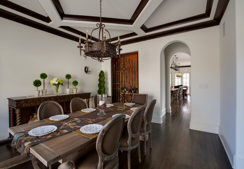 Cette photo montre une salle à manger ouverte sur la cuisine avec un mur blanc et parquet foncé.