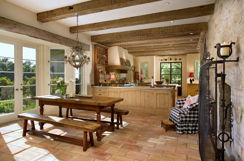 Cette image montre une très grande salle à manger ouverte sur la cuisine avec tomettes au sol.