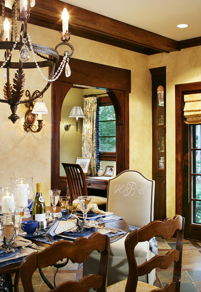 Esempio di una sala da pranzo aperta verso la cucina tradizionale di medie dimensioni con pavimento in ardesia, pavimento marrone, pareti beige e nessun camino