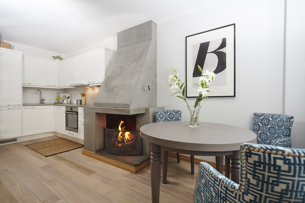 Example of a small transitional light wood floor and brown floor kitchen/dining room combo design in Other with gray walls, a standard fireplace and a concrete fireplace