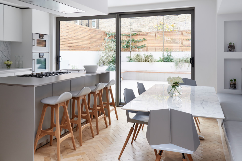 Medium sized contemporary kitchen/dining room in London with light hardwood flooring, beige floors and white walls.