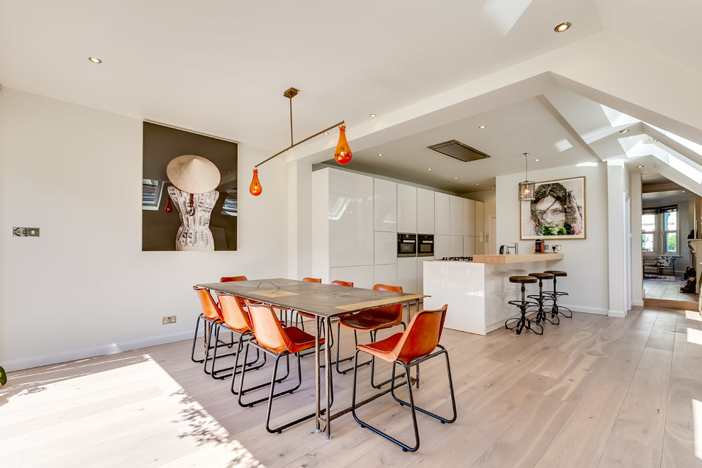 Contemporary kitchen/dining room in London with beige walls and light hardwood flooring.