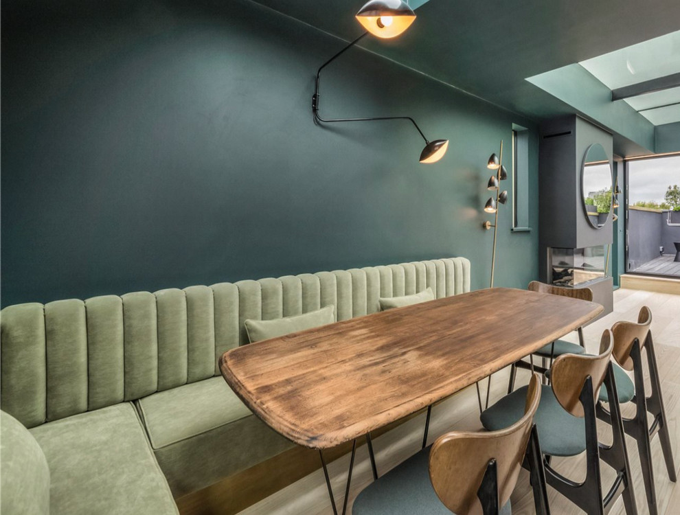 Стильный дизайн: гостиная-столовая среднего размера в стиле ретро с зелеными стенами, светлым паркетным полом, стандартным камином и бежевым полом - последний тренд