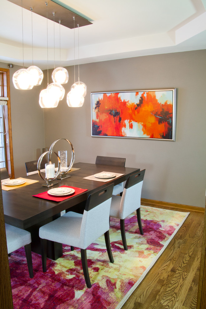 Idée de décoration pour une salle à manger ouverte sur le salon design de taille moyenne avec un mur gris, un sol en bois brun et aucune cheminée.