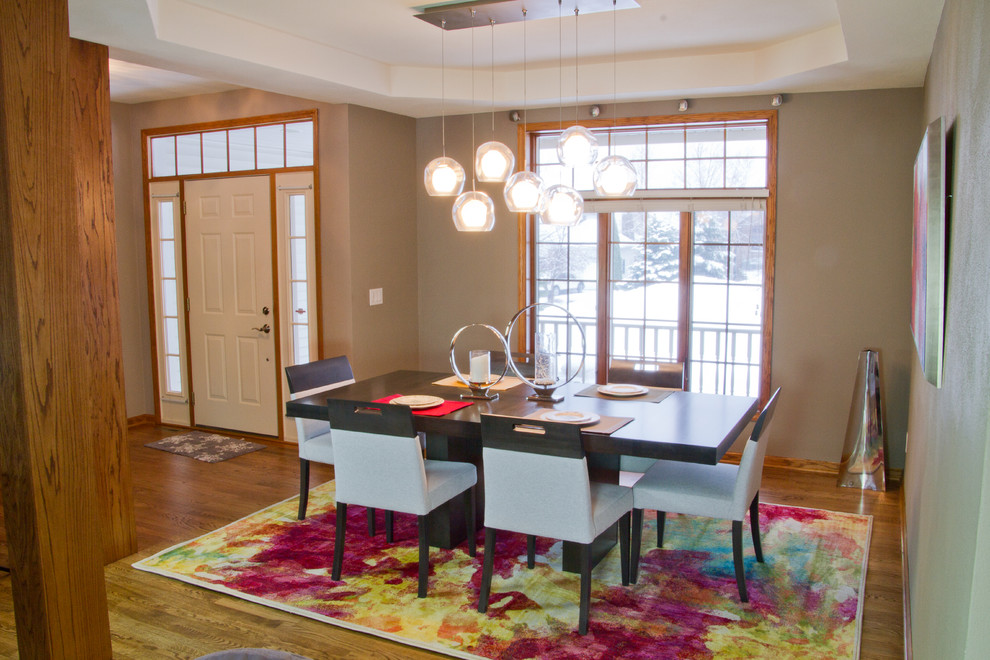 Immagine di una sala da pranzo aperta verso il soggiorno minimal di medie dimensioni con pavimento in legno massello medio, nessun camino e pareti grigie