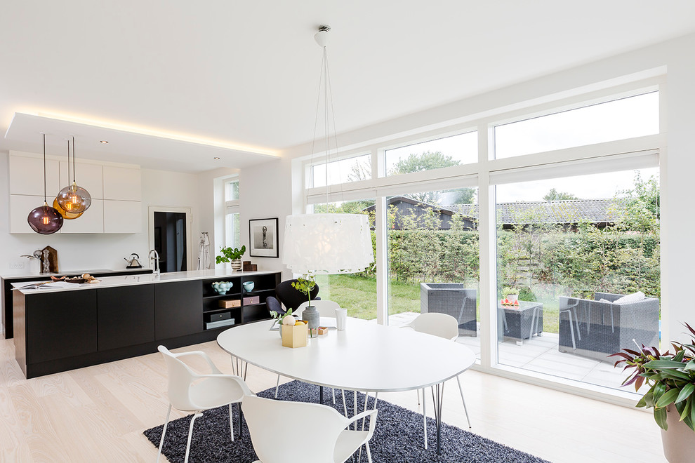 Cette image montre une salle à manger ouverte sur la cuisine minimaliste de taille moyenne avec un mur blanc.