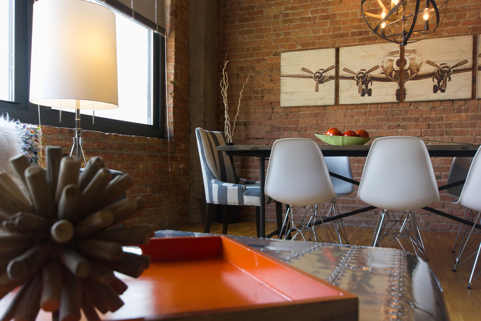 Immagine di una sala da pranzo aperta verso la cucina industriale di medie dimensioni con pareti rosse e parquet chiaro