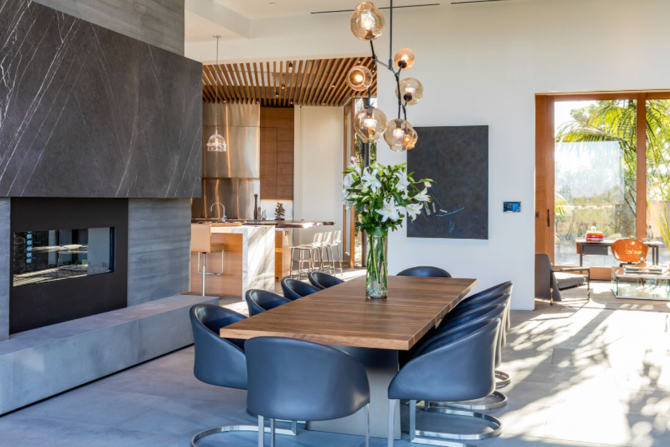 Inspiration for a large contemporary open plan dining room in Los Angeles with white walls, concrete flooring, a two-sided fireplace and grey floors.