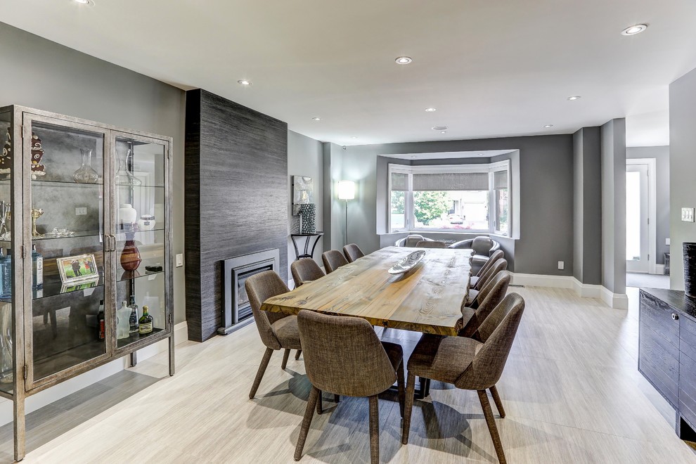 На фото: огромная кухня-столовая в современном стиле с серыми стенами, полом из керамогранита, стандартным камином, фасадом камина из плитки и серым полом