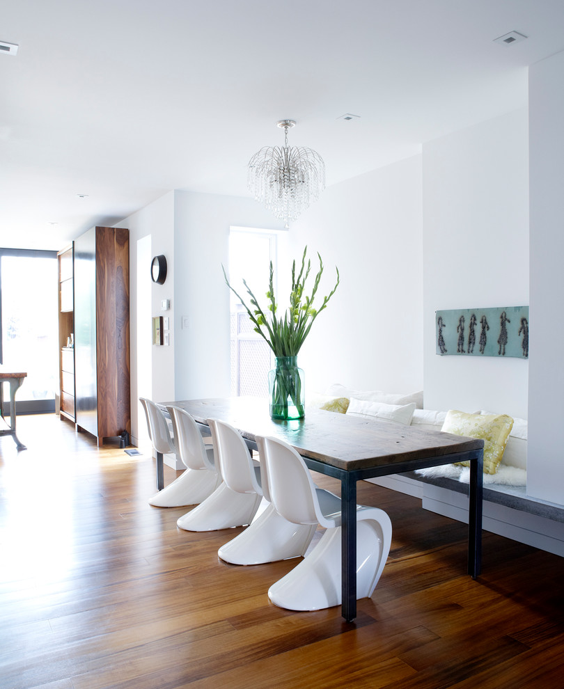Cette photo montre une salle à manger ouverte sur le salon tendance avec un mur blanc et parquet foncé.