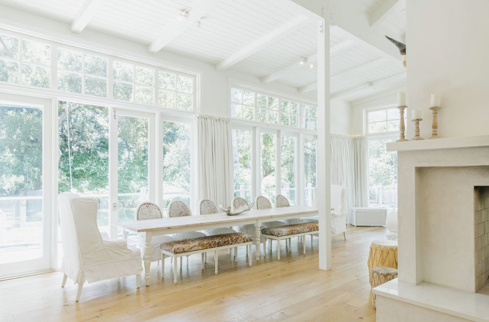 Idée de décoration pour une salle à manger ouverte sur le salon champêtre avec un mur blanc, parquet clair, une cheminée double-face, un manteau de cheminée en pierre, un sol marron et un plafond en lambris de bois.