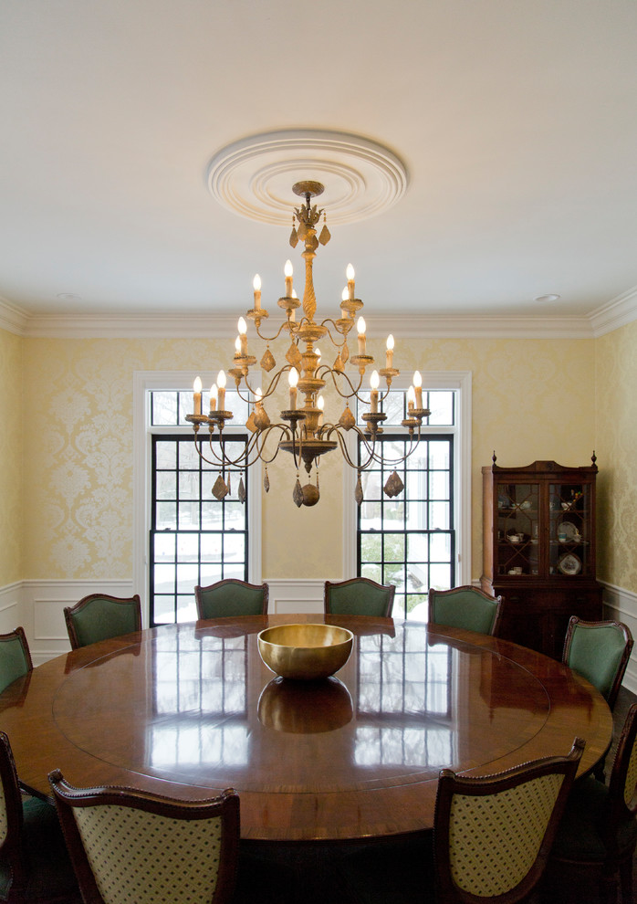Immagine di una grande sala da pranzo tradizionale chiusa con pareti gialle, parquet scuro e pavimento marrone