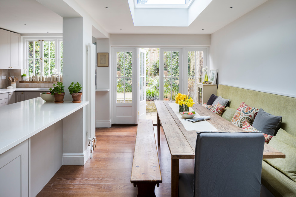 Esempio di una sala da pranzo aperta verso la cucina chic con pareti bianche, pavimento in legno massello medio e pavimento marrone
