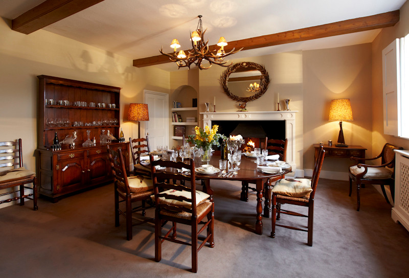 Immagine di una sala da pranzo classica chiusa e di medie dimensioni con pareti beige, moquette e cornice del camino in legno