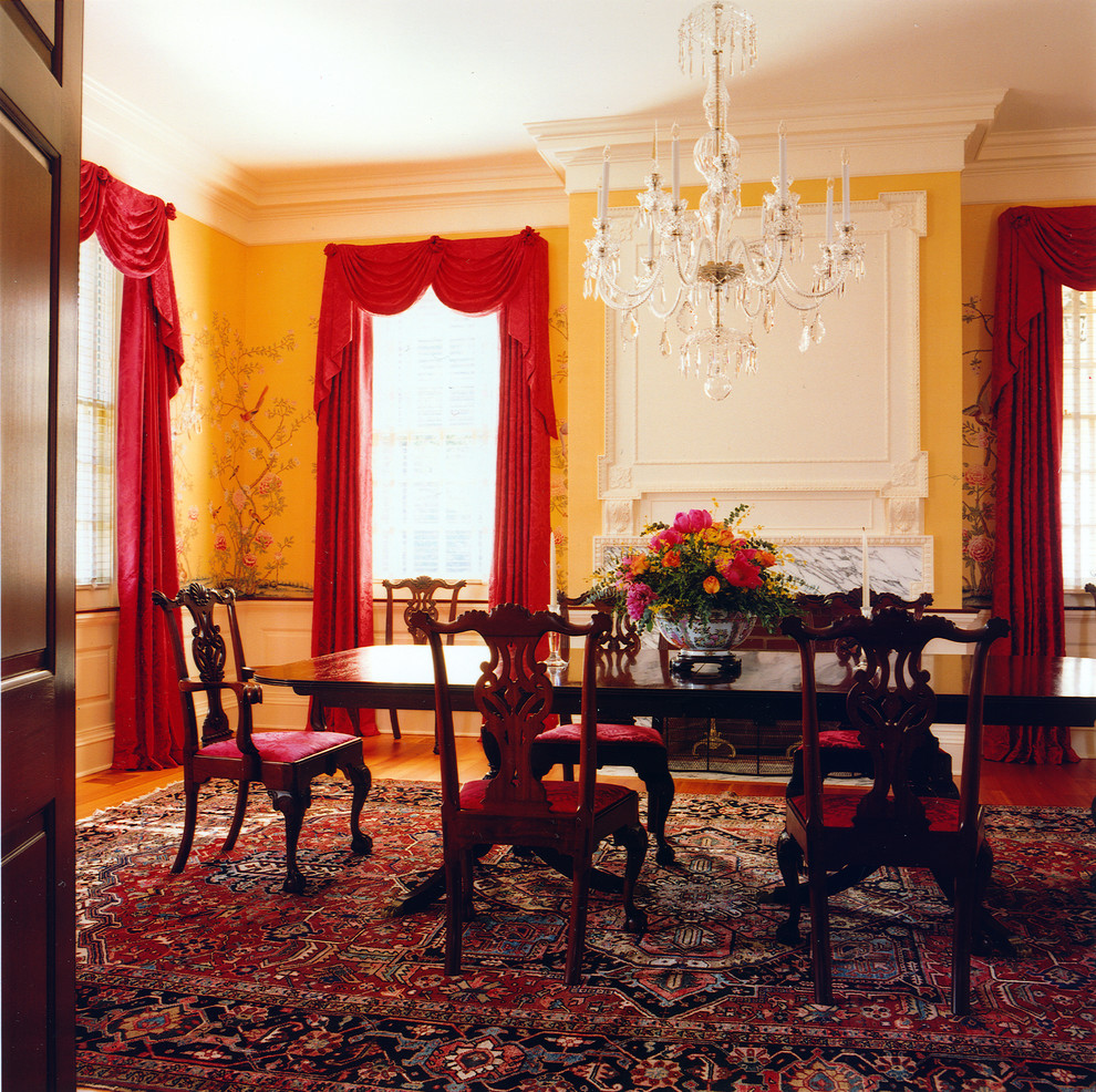 Источник вдохновения для домашнего уюта: отдельная столовая в классическом стиле с паркетным полом среднего тона, стандартным камином, фасадом камина из камня и желтыми стенами