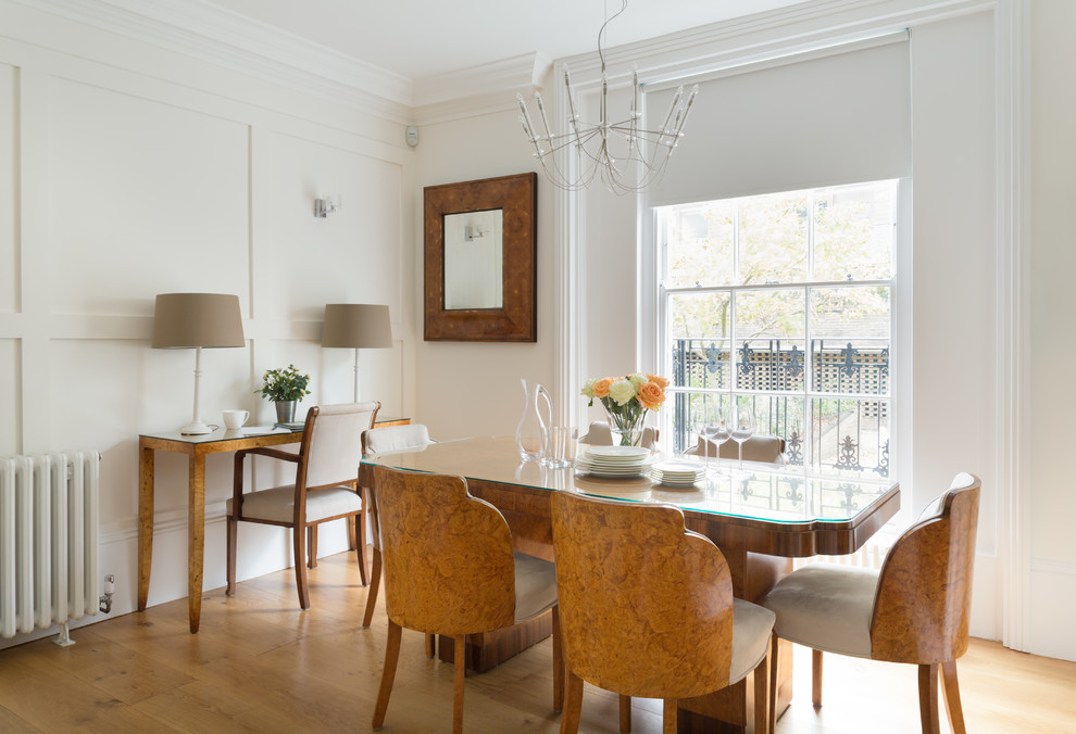Photo of a medium sized classic dining room in London with grey walls, light hardwood flooring, a standard fireplace and a stone fireplace surround.