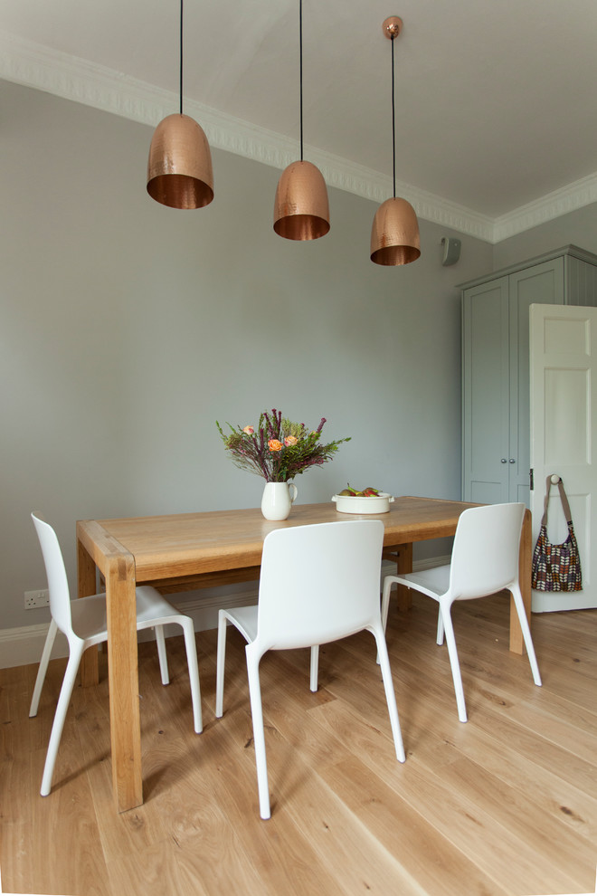 Cette photo montre une salle à manger ouverte sur la cuisine chic avec un sol en bois brun et un mur gris.