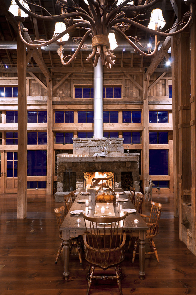 Example of a country dark wood floor dining room design in Cleveland with a stone fireplace