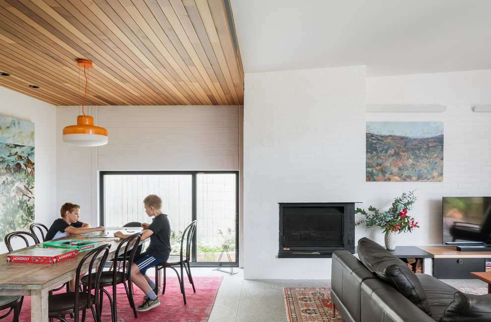 Offenes, Mittelgroßes Modernes Esszimmer mit weißer Wandfarbe, Betonboden, Kaminofen, Kaminumrandung aus Backstein und grauem Boden in Sydney