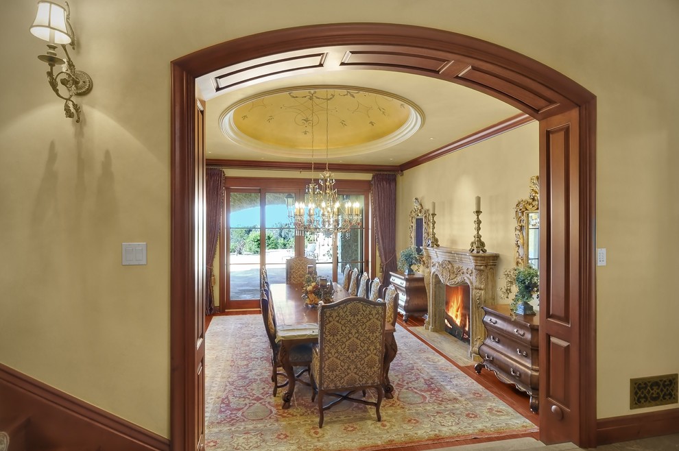 Geräumiges, Geschlossenes Klassisches Esszimmer mit beiger Wandfarbe, braunem Holzboden, Kamin, Kaminumrandung aus Beton und braunem Boden in San Diego